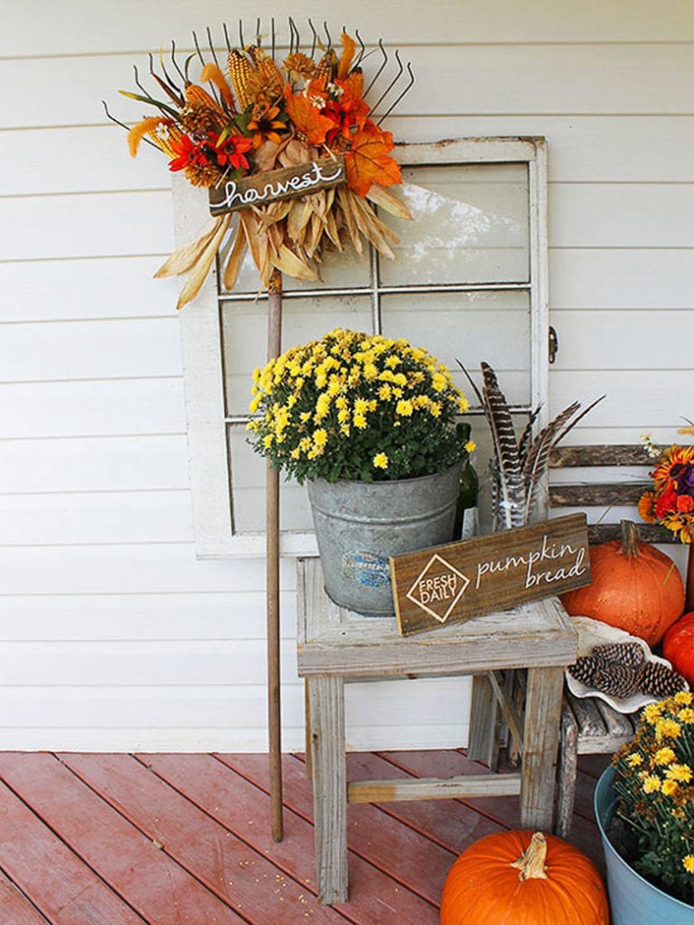 farmhouse fall decorations with reclaimed windows, rusty rake, tin buckets, mums, and pumpkins